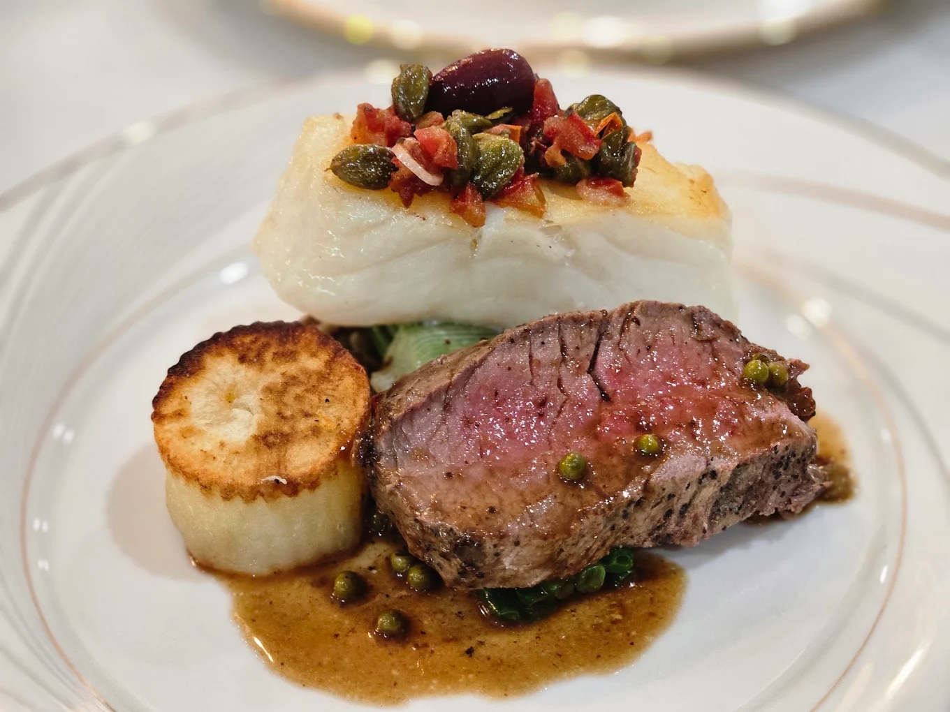 Fine dining plated course with beef, seared potato, and cod