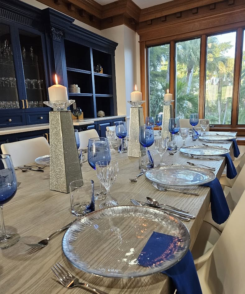Elegant private dining table with blue glassware, crystal candle holders, and polished place settings